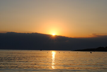 sunset at the beach beyond clouds and sea