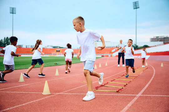 Little boy running during exercise class at stadium.
