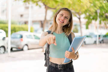 Fototapeta premium Young blonde student woman at outdoors points finger at you with a confident expression