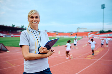 Portrait of happy physical education teacher at stadium looking at camera.