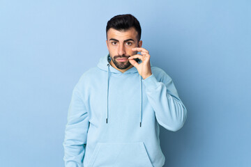 Caucasian man over isolated blue background showing a sign of silence gesture