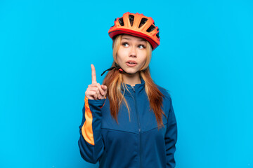 Young cyclist girl isolated on blue background thinking an idea pointing the finger up