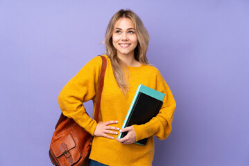 Teenager Russian student girl isolated on purple background posing with arms at hip and smiling