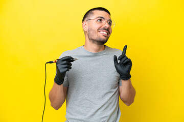Tattoo artist caucasian man isolated on yellow background pointing up a great idea