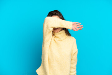 Young caucasian woman isolated on blue background covering eyes by hands