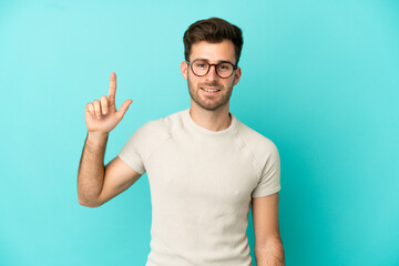 Naklejka premium Young caucasian handsome man isolated on blue background pointing up a great idea