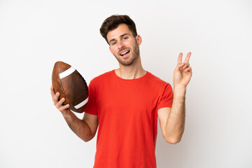 Young caucasian man playing rugby isolated on white background smiling and showing victory sign