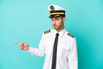 Airplane caucasian pilot isolated on blue background pointing finger to the side