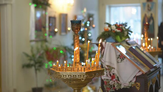 Lighting wax candles inserted in sand burning in temple spreading light on blurred background. Worship traditions in Christian church close view