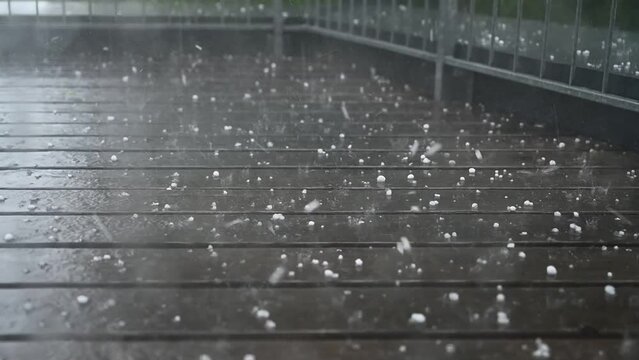 Hagel prasselt auf Holzterrasse