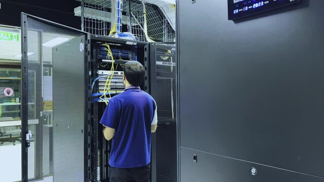 Computer engineer working with supercomputer in data center. Technician connecting cable on server in server room. system administrator setting up server network and doing maintenance.