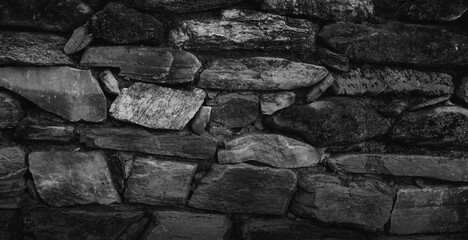 Empty monochrome black and white grain stone wall for abstract  background and texture. beautiful patterns, space for work, banner, wallpaper close up. Horizontal.