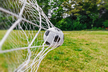 textured soccer game field with ball in the goal net, soccer goal.