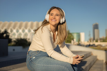 Fototapeta na wymiar chica joven alegre escuchando música con auriculares por la calle
