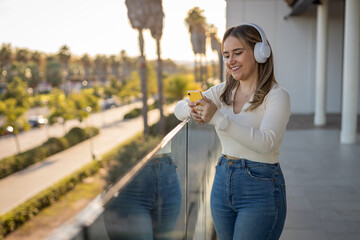 chica joven alegre escuchando música con auriculares por la calle
