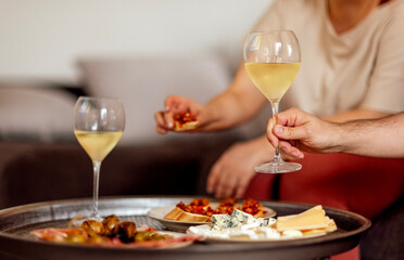Two glasses of cool champagne and plates with various snacks on a round metal coffee table