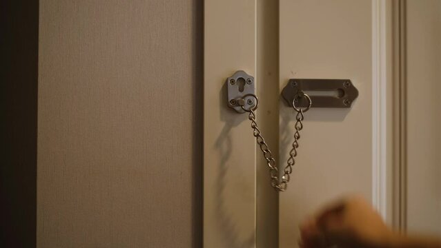 a man closes the door from the inside with a lock and chain and does not let the robber 