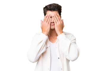 Young handsome caucasian man over isolated background covering eyes by hands
