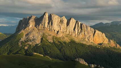 View of the majestic sheer cliff in the pre-sunset light. Mount Chertovy Vorota at sunset. Beautiful mountain landscape. - obrazy, fototapety, plakaty