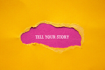 Tell your story lettering on ripped orange paper with pink background. Conceptual photo. Top view,...