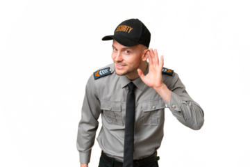 Young security caucasian man over isolated background listening to something by putting hand on the ear