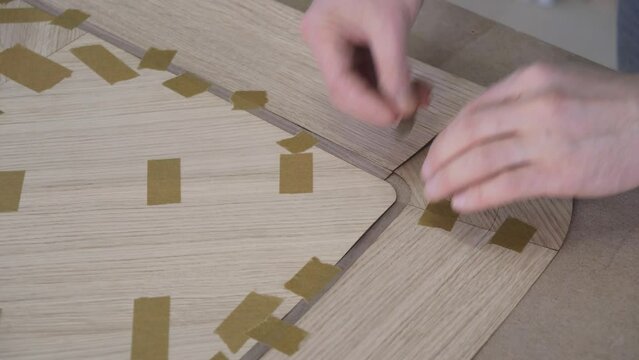 Carpenter joints veneer with tape for table top of dining table with geometric pattern on workbench in workshop upper close view