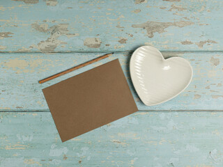 Heart shaped plate, paper, pencil on vintage wooden background. Top view. - 704561789