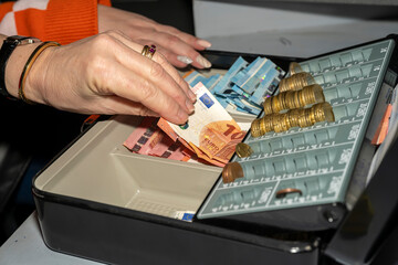 caisse enregistreuse avec des billets et des pièces en euros manipulée par une femme - obrazy, fototapety, plakaty
