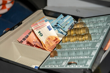 caisse en létal et plastique avec de l'argent liquide en euros, pièces et billets