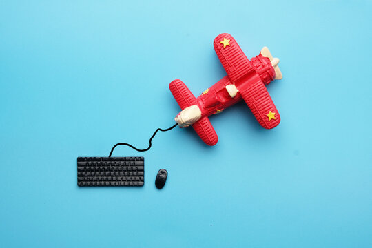 A flatlay picture of miniature keyboard and aircraft on blue background. Search the flight concept.