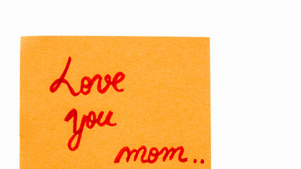 Love you mom handwriting text close up isolated on orange paper with copy space. Writing text on memo post reminder.