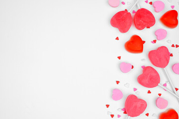 Valentines Day side border of candy hearts and sprinkles. Overhead view on a white background. Copy space.