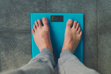 Man standing on weight scale - obrazy, fototapety, plakaty