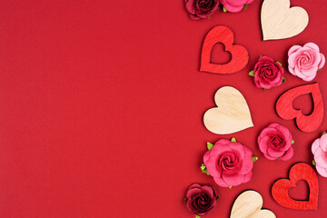 Valentines Day side border of wooden hearts and roses. Overhead view on a red banner background....