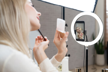 Rear view young woman making beauty and cosmetic tutorial video content for social media. Beauty...