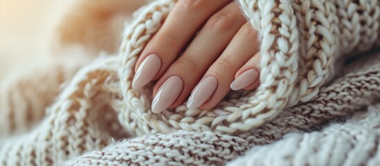 Beautifully manicured nails on a cozy sweater with a scarf. Nail care concept.