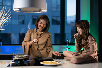 Mother and daughter cooking pancakes in their kitchen 