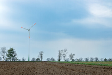 A field prepared for sowing, a wind turbine against the sky at the end. The haze