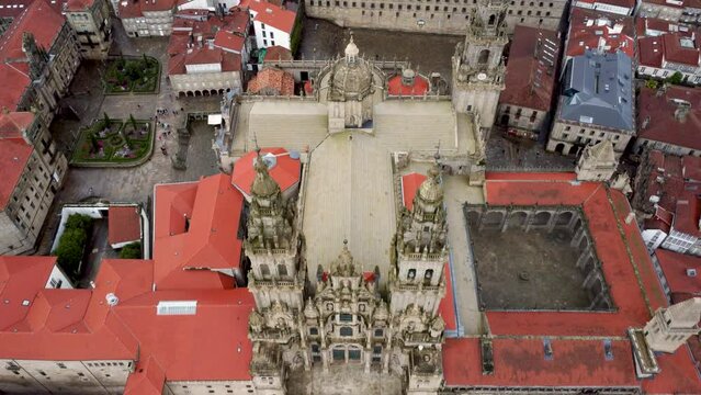 Cinematic aerial view of Santiago de Compostela Cathedral. Drone starting from above the cathedral with camera in tilt down position and going backward slowly revealing the all the cathedral and city.