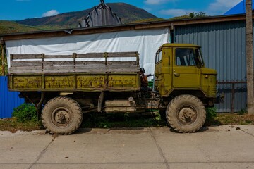Obraz premium an old Russian army cargo SUV in khaki color stands on a sunny summer day