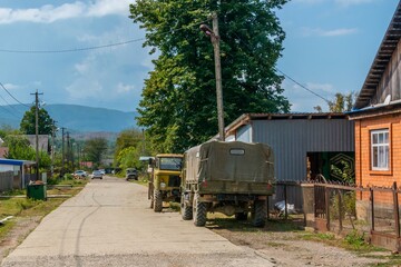Obraz premium cars - SUVs on the street of a farm in the mountains of the Western Caucasus (South of Russia) on a sunny day at the end of summer