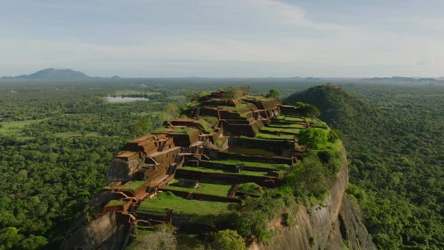 Aerial footage of ruins of ancient palace on top of high rock surrounded by forests. Sigiriya, Sri Lanka