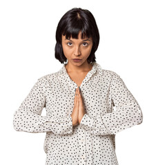 Young Hispanic woman with short black hair in studio praying, showing devotion, religious person...