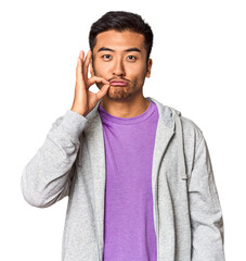 Athletic Chinese man in sportswear in studio with fingers on lips keeping a secret.