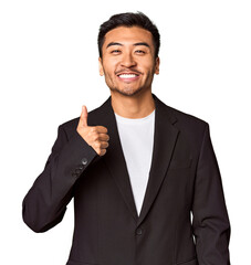 Young Chinese man in business suit in studio smiling and raising thumb up