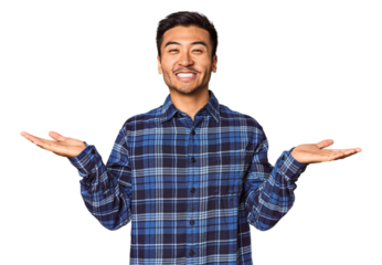 Young Chinese man in studio background makes scale with arms, feels happy and confident.
