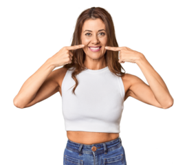 Middle-aged woman portrait in studio setting smiles, pointing fingers at mouth.