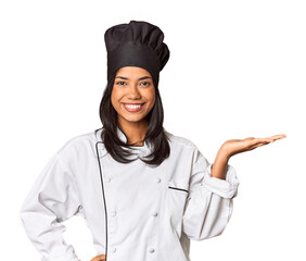 Young Filipina chef with cooking hat in studio showing a copy space on a palm and holding another...