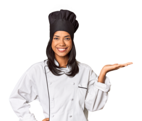 Young Filipina chef with cooking hat in studio showing a copy space on a palm and holding another hand on waist.
