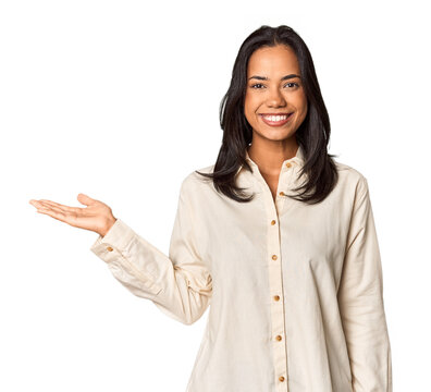 Young Filipina with long black hair in studio showing a copy space on a palm and holding another hand on waist.